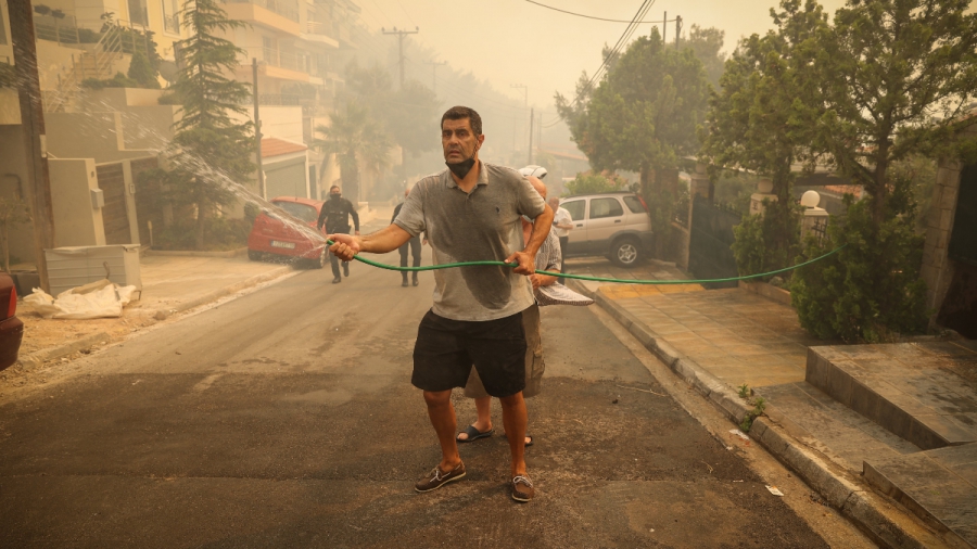 Ο Δημήτρης Καζάζης προσπαθεί με λάστιχο να σβήσει τη φωτιά στη Βούλα